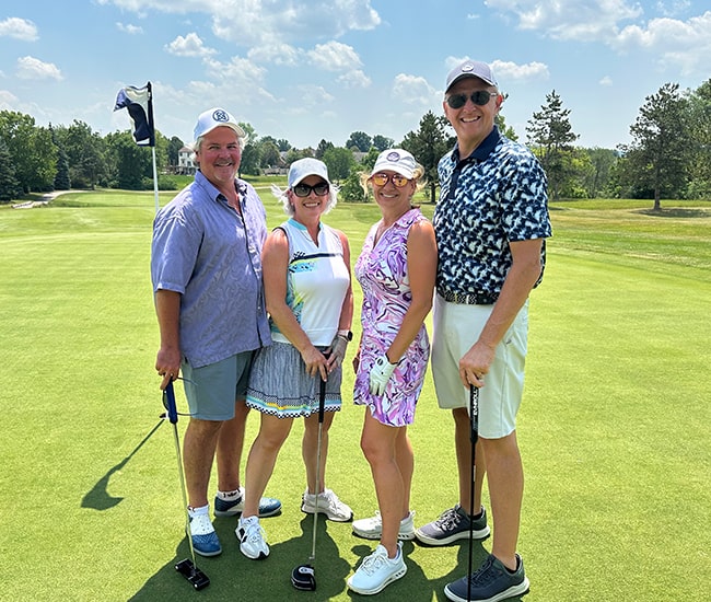 Four smiling golfers standing on the green at Stonewater Country Club during the Starfysh Golf Classic.