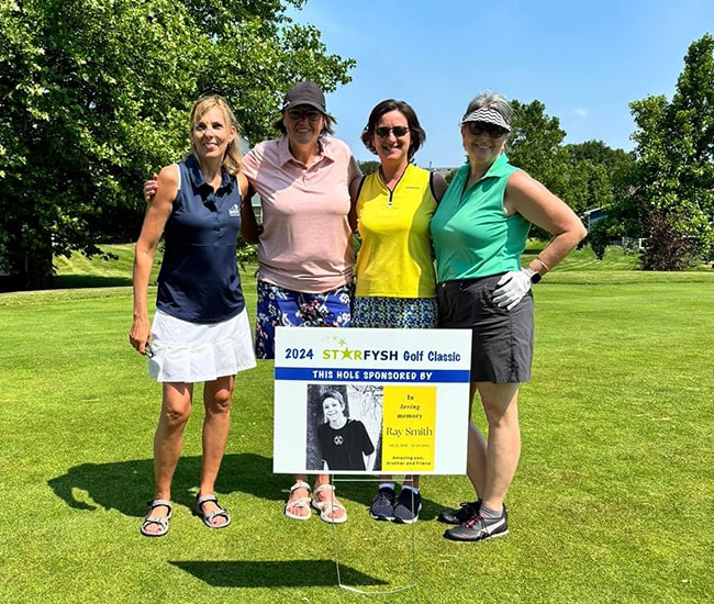 Group of golfers by a memorial hole sponsorship sign at the 2024 Starfysh Golf Classic.