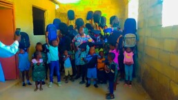 Students on La Gonave smiling and holding their backpacks at a Starfysh-supported school.