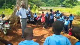 Pastor Charles Eveny leading an outdoor outreach session with children on La Gonave.